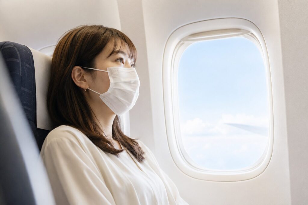 飛行機でマスクをつける女性